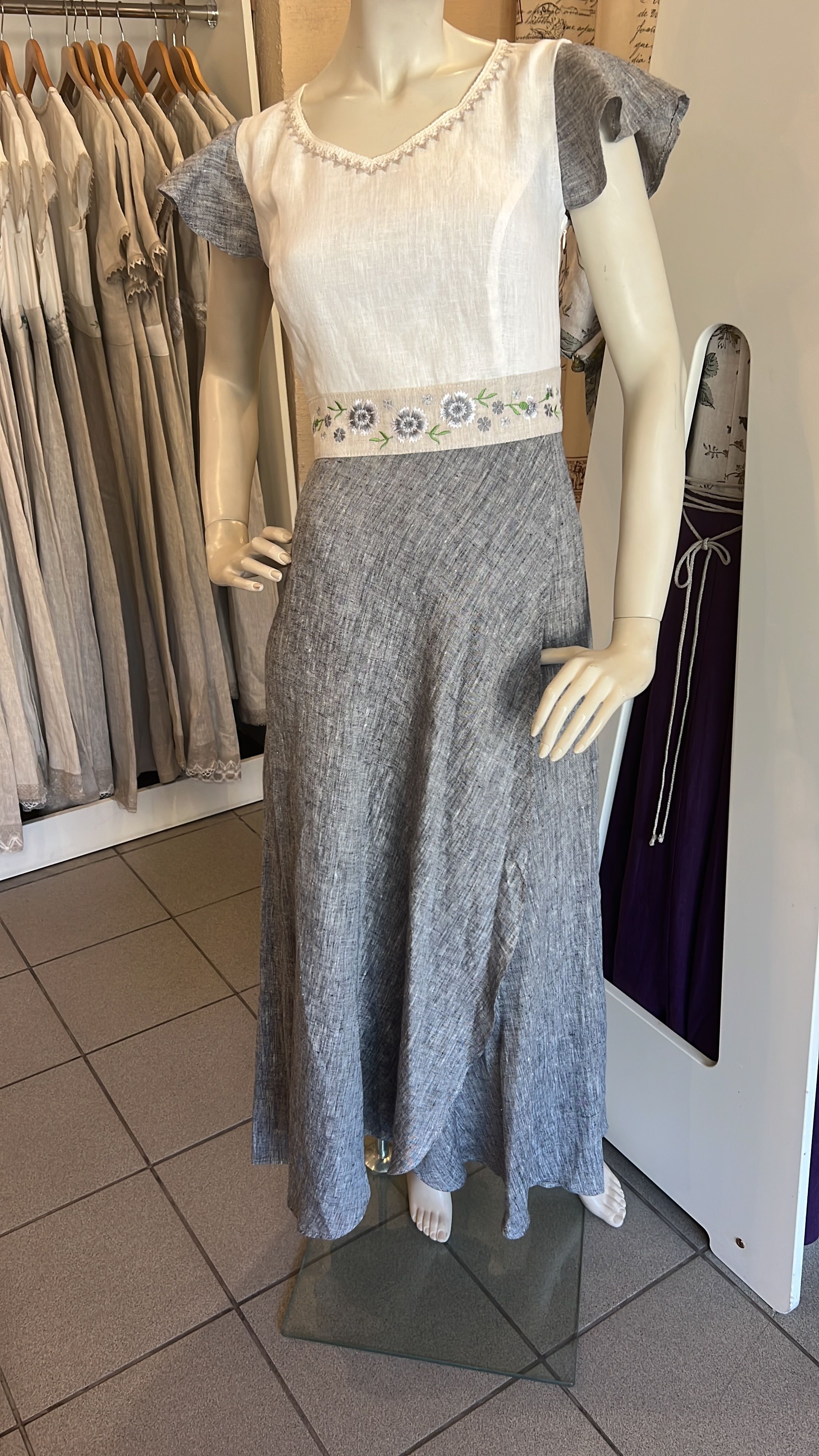 Linasest naiste pikk maani kleit salongis seisva mannekeni seljas