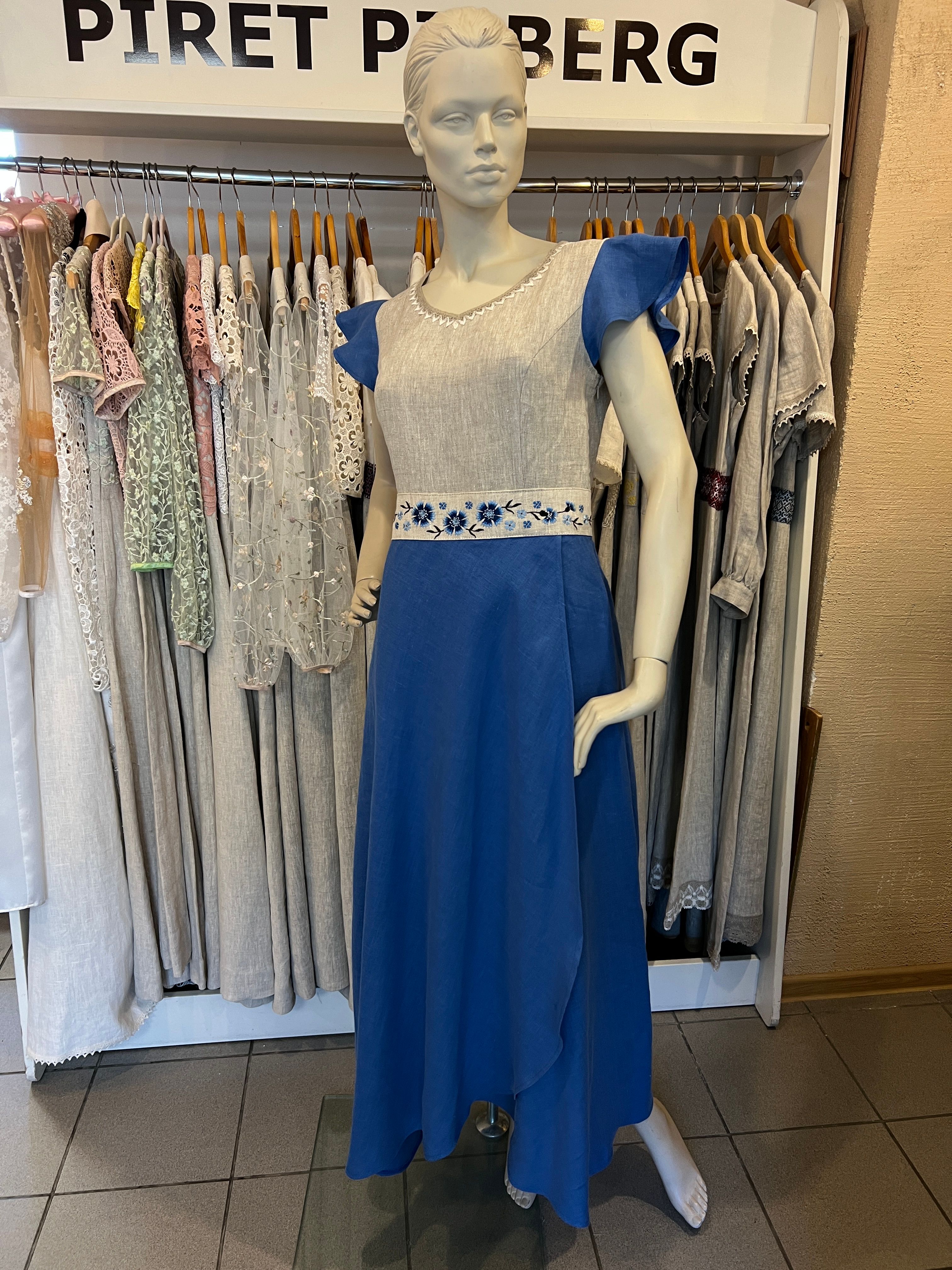 Linast rahvuslik sinise-valgekirju kleit salongis seisva mannekeeni seljas