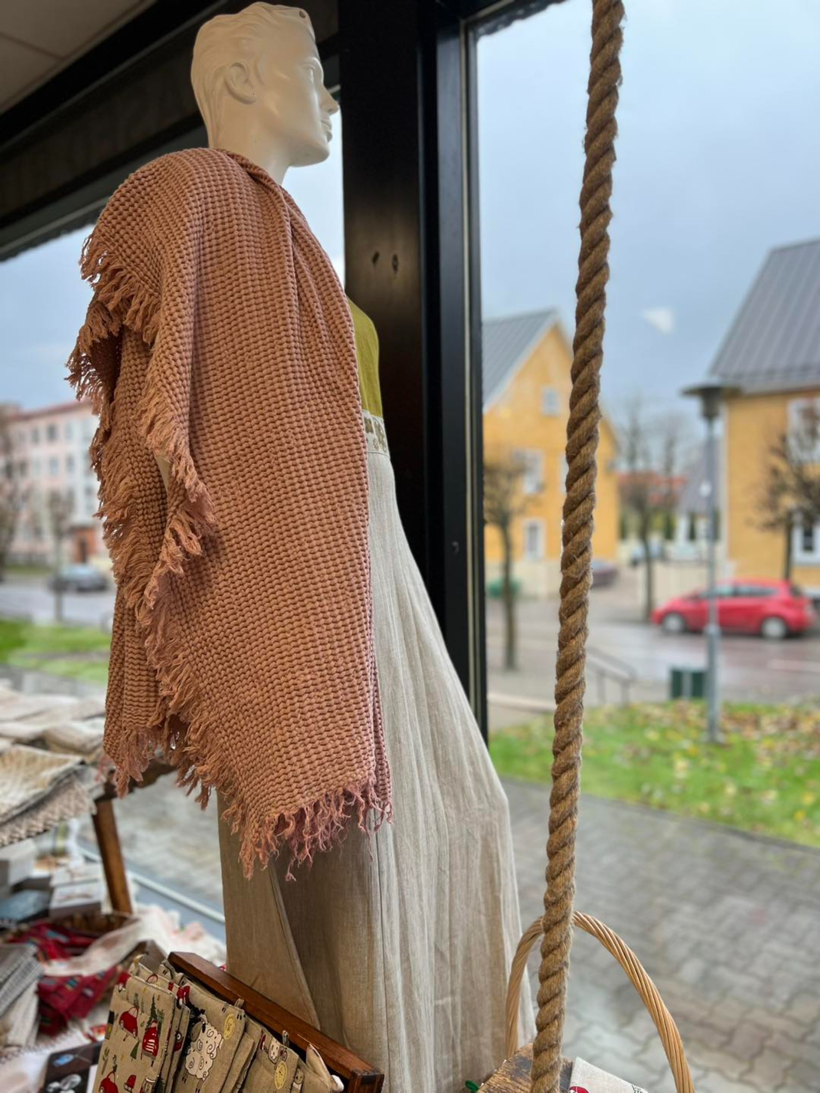 Mannekeen kaupluse vaateaknal seismas, seljas pruun linast kangas