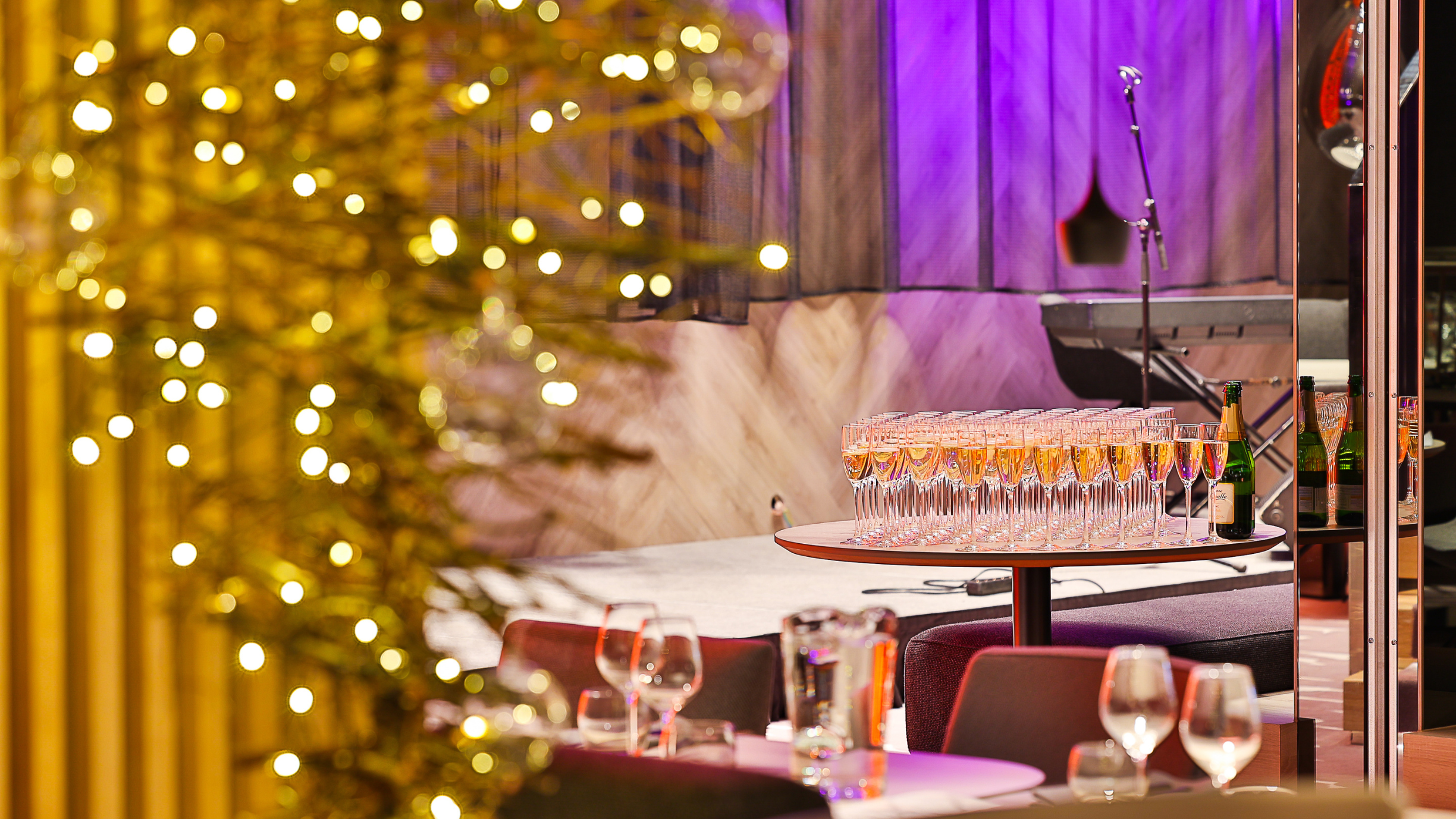 Vahuveinilaud piduliku kattega restoranis, sisekujunduses näeb heledaid toone ja modernset kuuske.