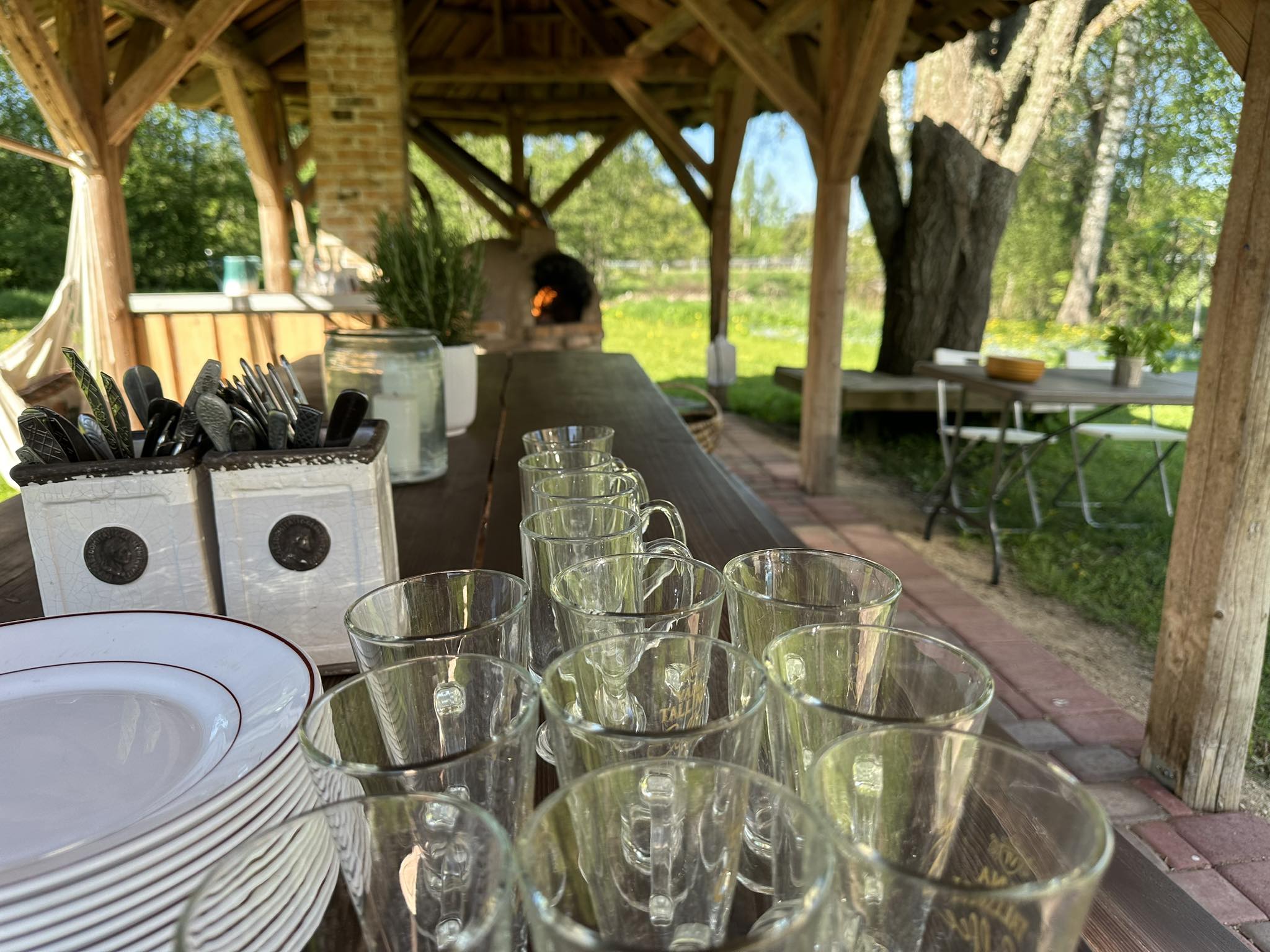 Hellenurme Veskimuuseumi õueala, kus kaetakse laud ja küpsetatakse pitsat puuküttega ahjus.