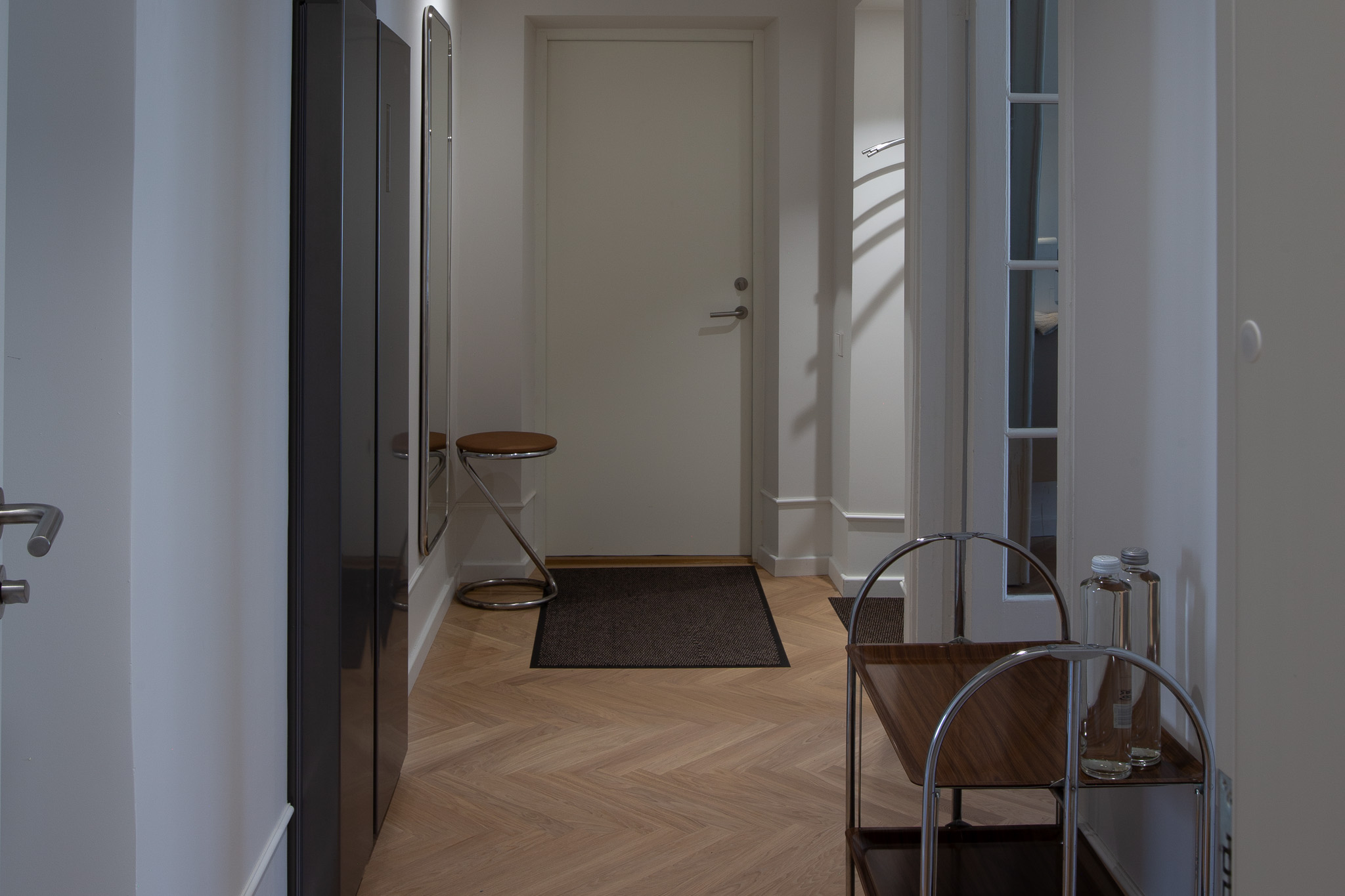 Dzīvoklis Tartu Rātslaukumā - koridors ar gaišām sienām, lielu spoguli, tumšu skapi un paklāju