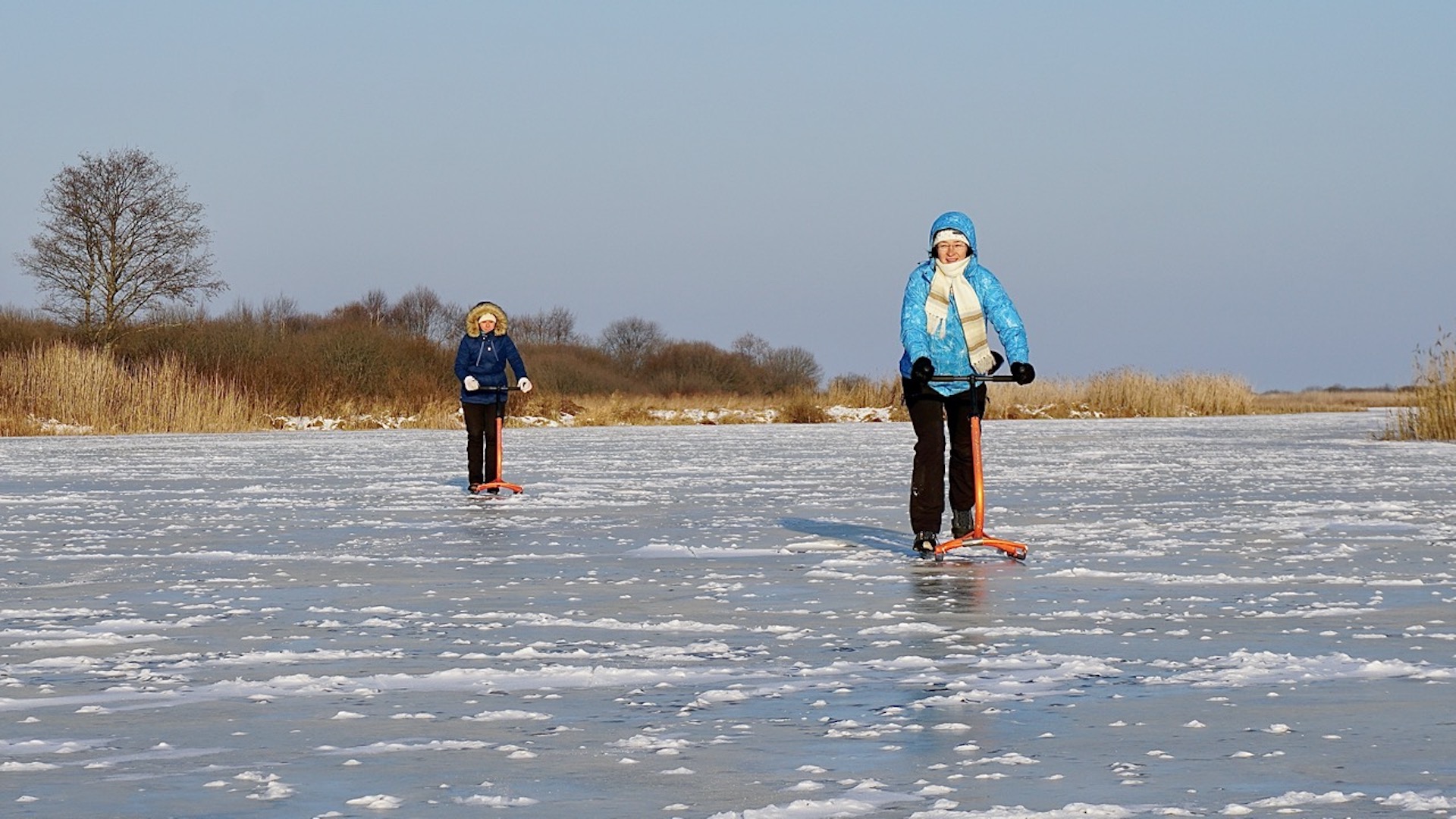 Kick sledding trip on Võhandu in excellent ice conditions, two travelers push sleds on glass ice.