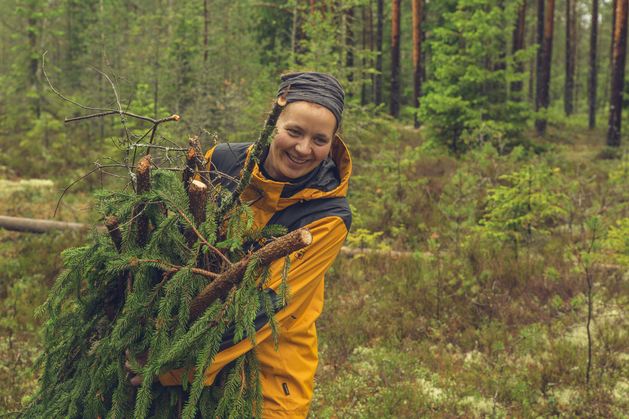 Teilnehmerin sammelt Äste im Wald, um einen Unterschlupf zu bauen.
