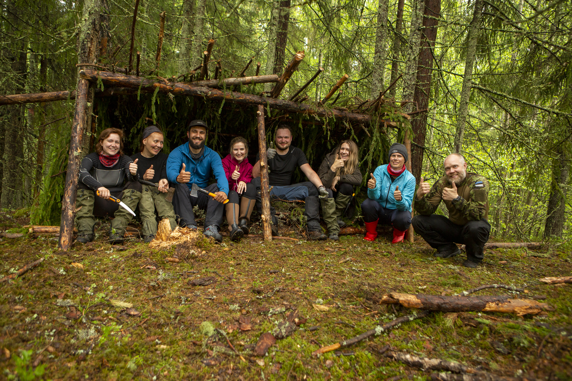 Eine Gruppe in einem selbstgebauten Unterschlupf im Wald.