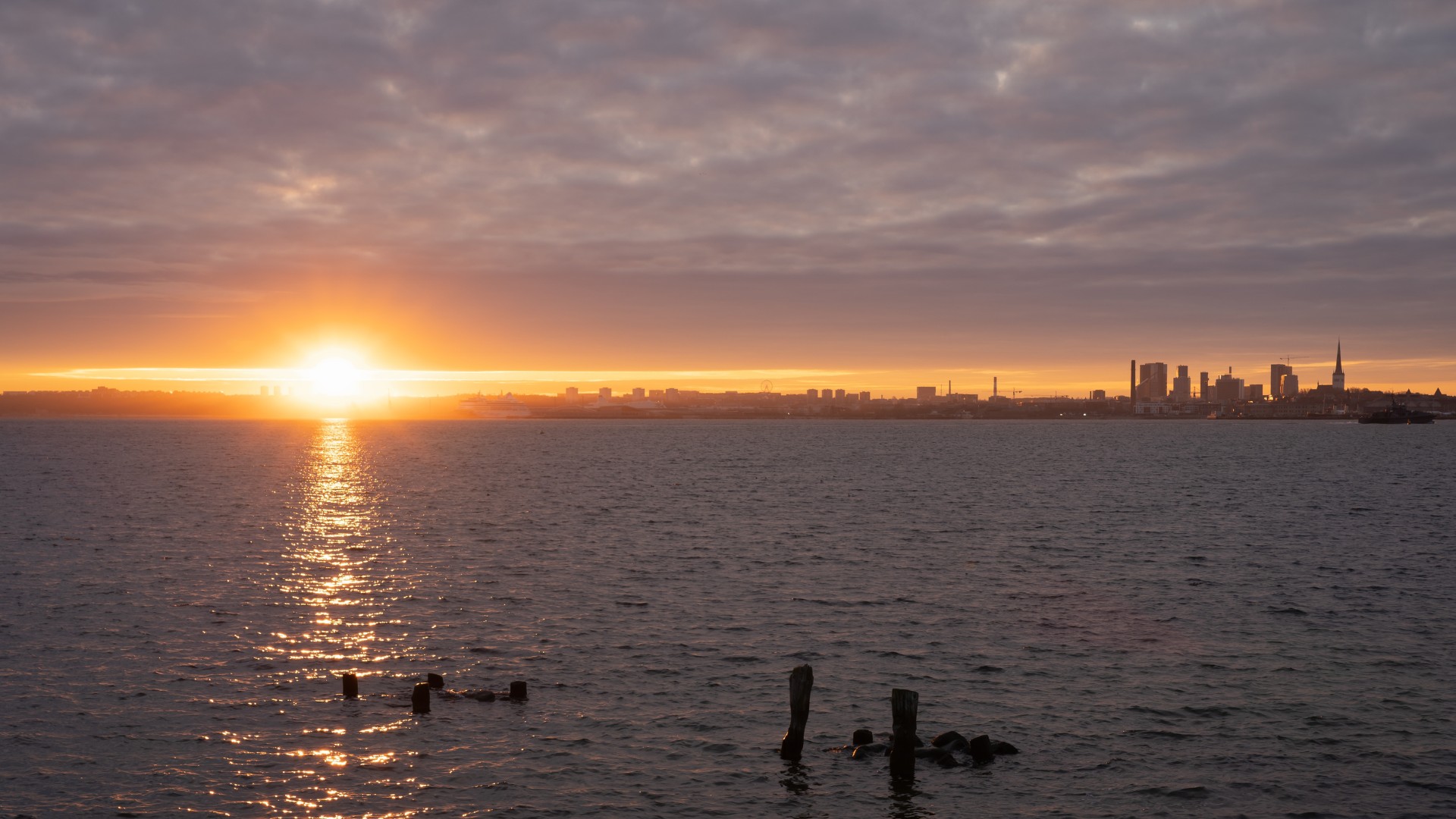 Sonnenuntergang über dem Meer mit der Skyline von Tallinn im Hintergrund