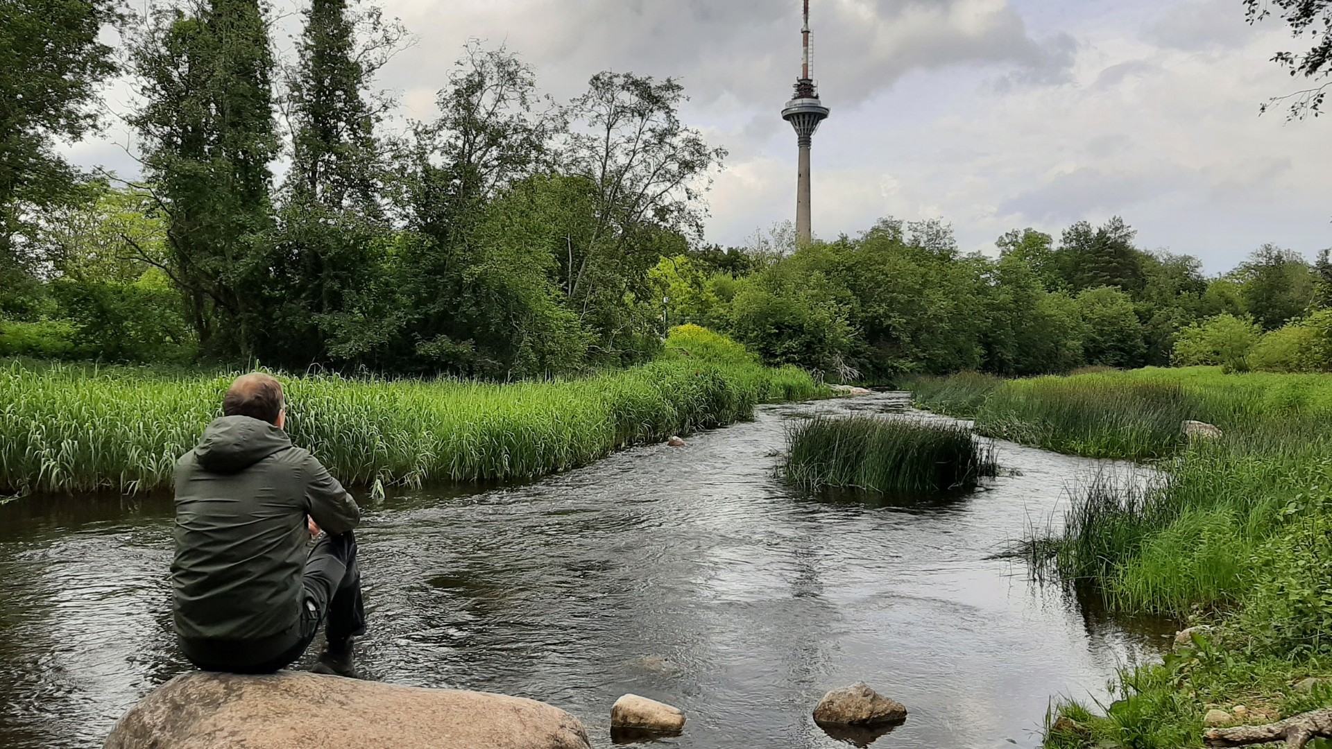 Pirita jões oleval suurel kivil istuv inimene vaatamas Tallinna teletorni
